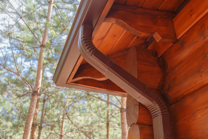 Roof fascia board. Roof gutter system on log house in forest.